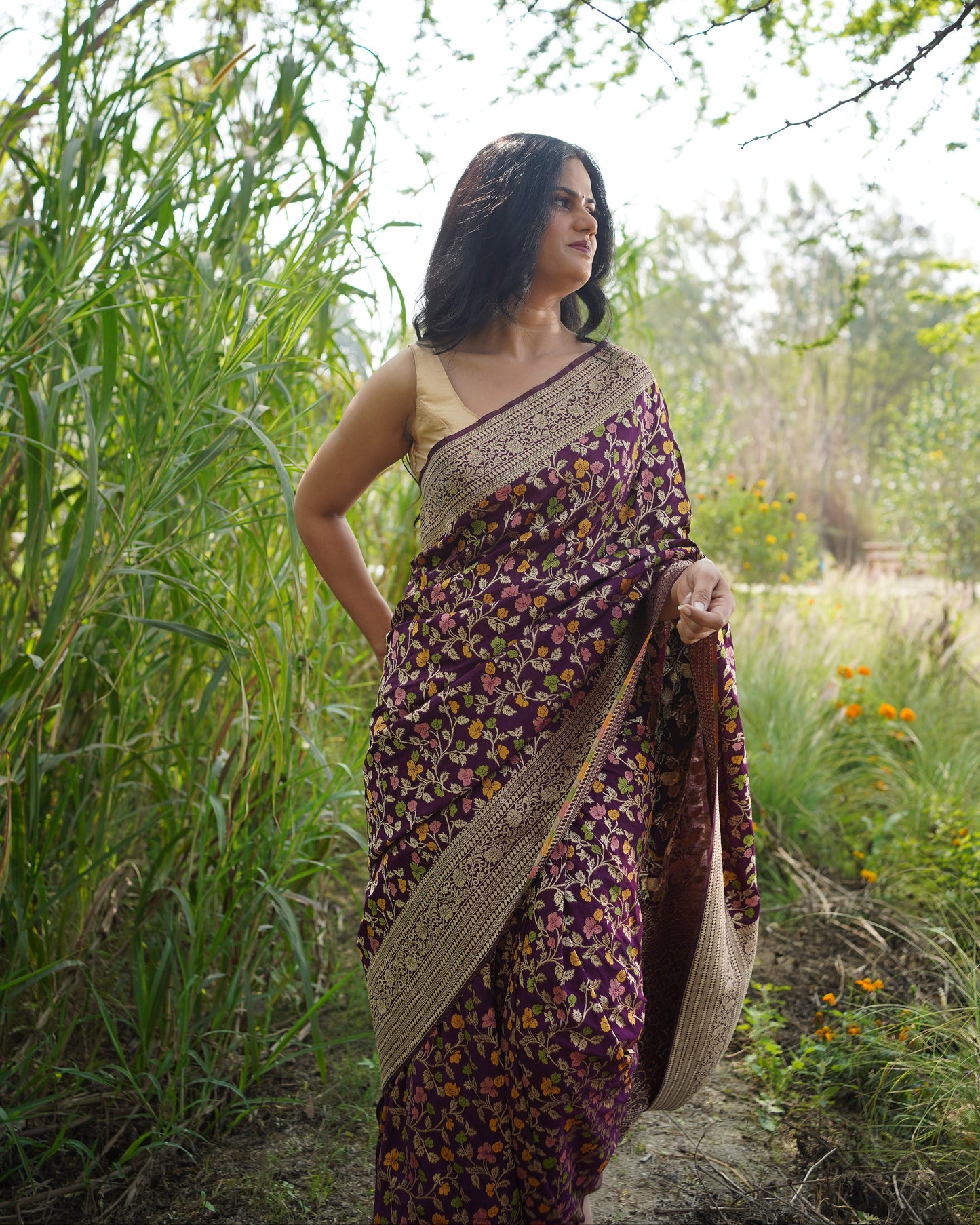 Woman in a patterned dress standing outdoors with greenery around