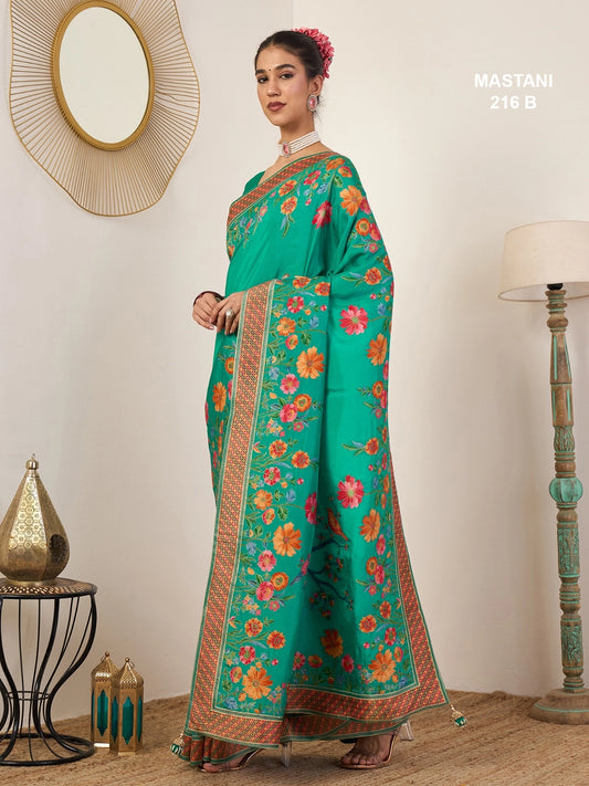 Woman in a green floral saree standing in a room with decorative elements.