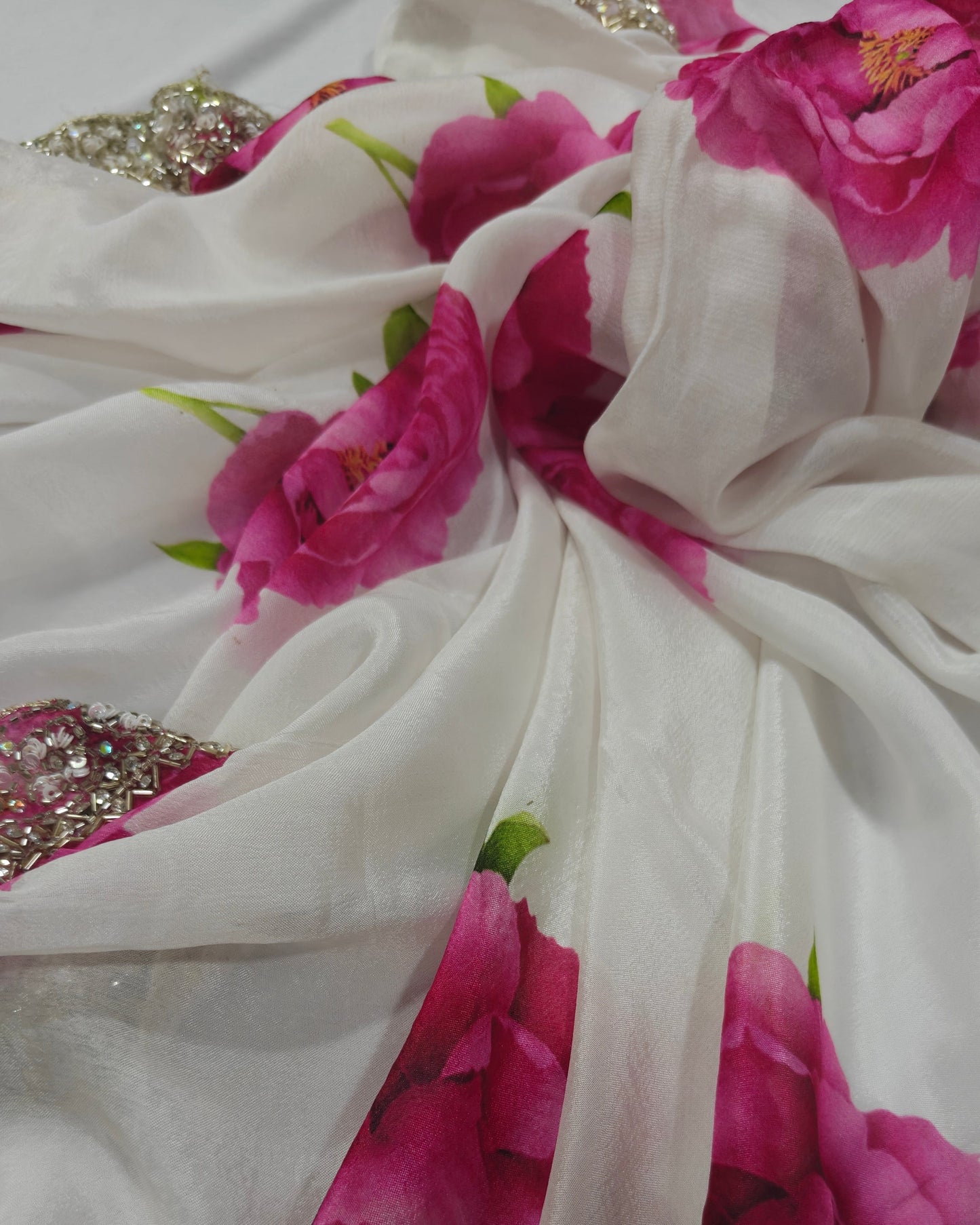 Close-up of a white fabric with pink floral patterns and decorative elements.