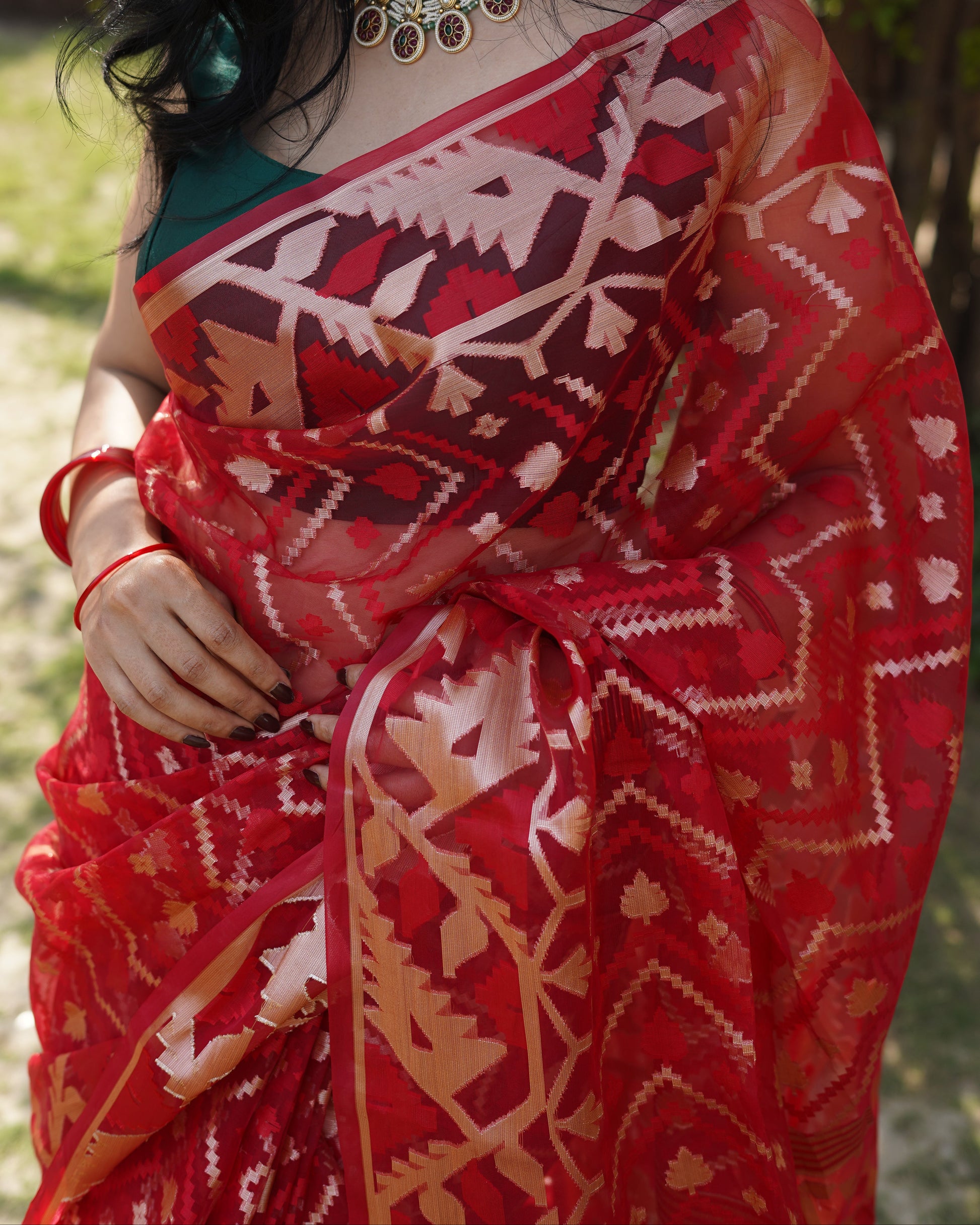 Person wearing a red and white patterned garment with a blurred natural background