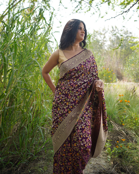 Woman in a patterned dress standing outdoors with greenery around