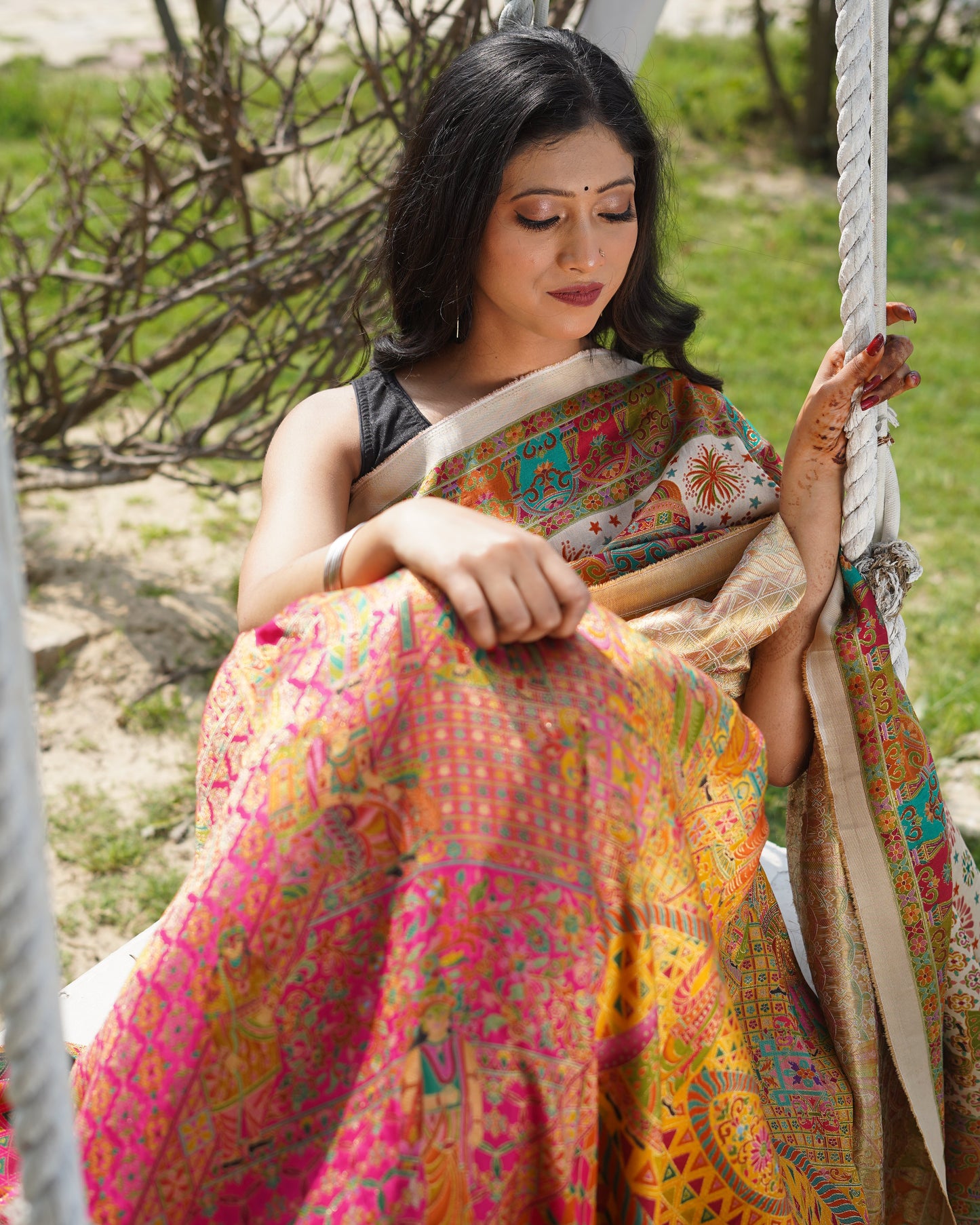 Woman in a colorful dress sitting on a swing with a natural background