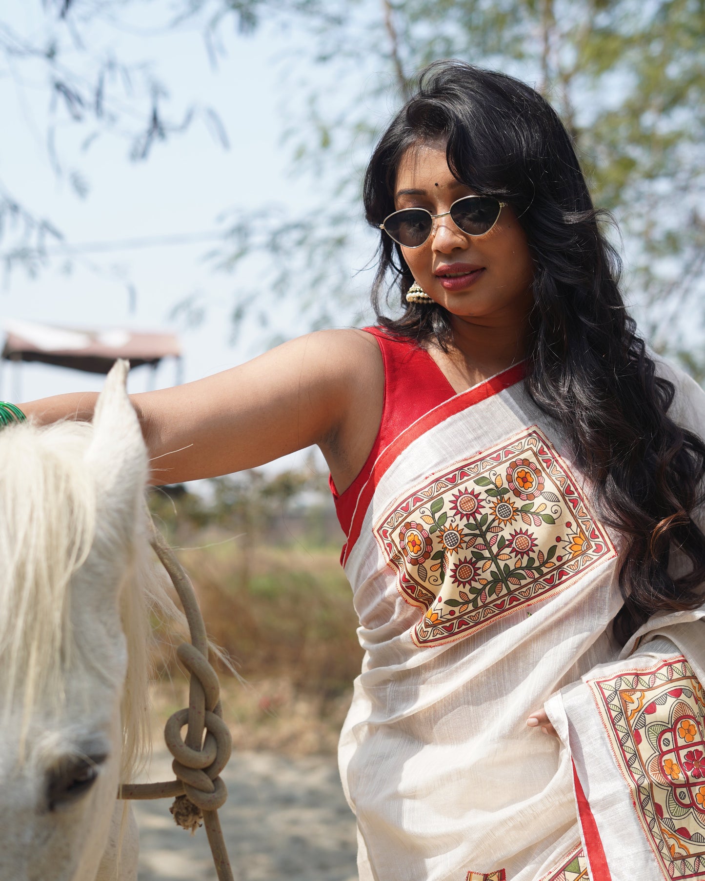 Woman wearing a traditional outfit with intricate patterns, standing outdoors.