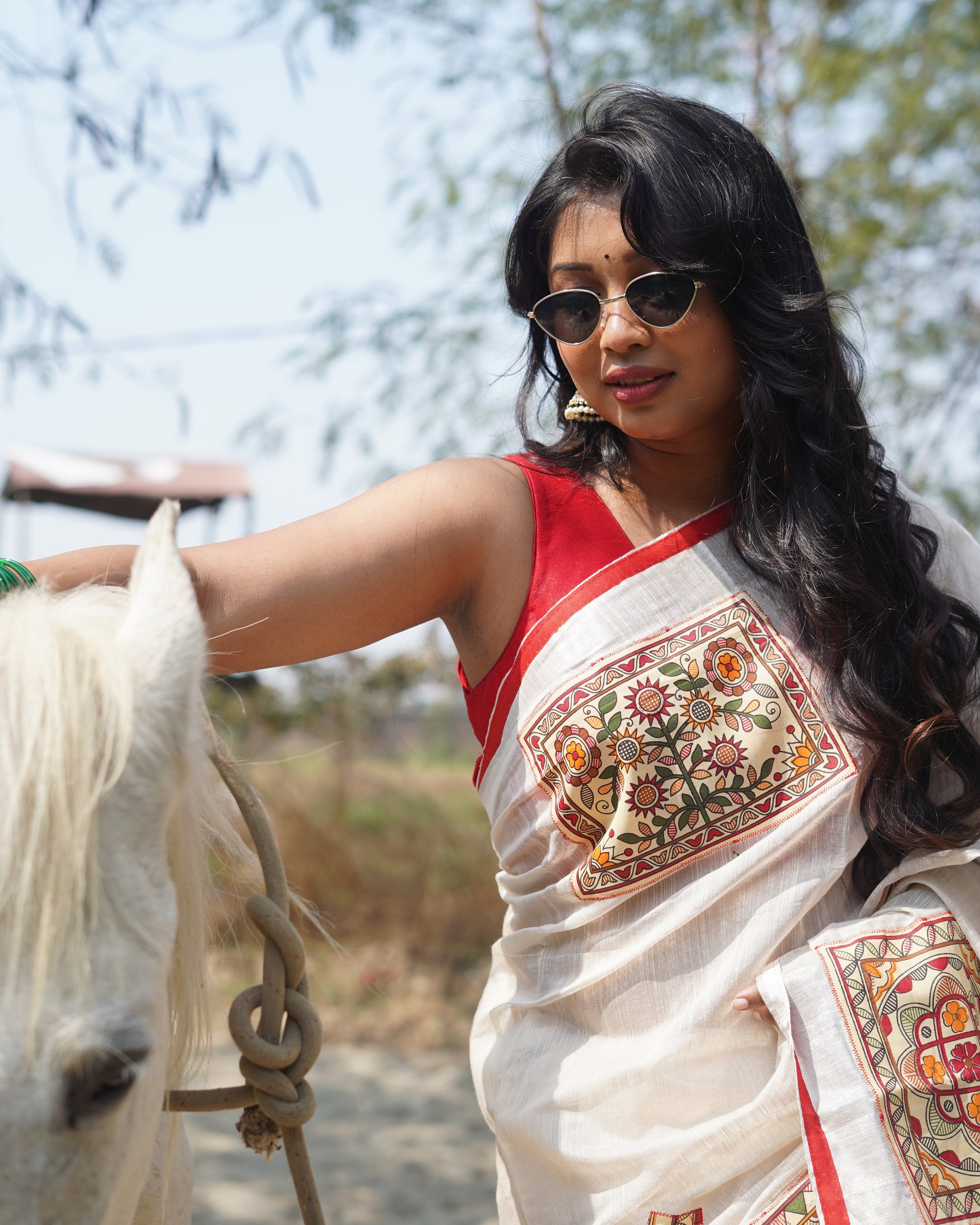 Woman wearing a traditional outfit with intricate patterns, standing outdoors.