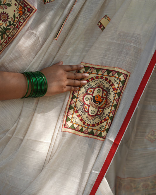 Decorative fabric with intricate patterns and a hand wearing green bangles.