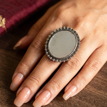 Close-up of a hand wearing an ornate silver ring on a wooden surface