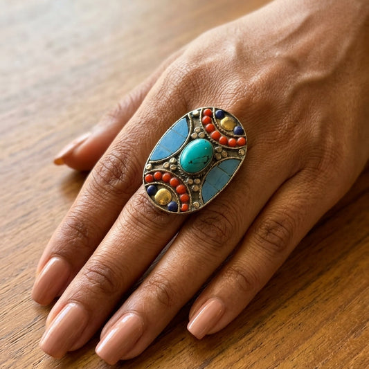 Hand wearing a colorful ring on a wooden surface