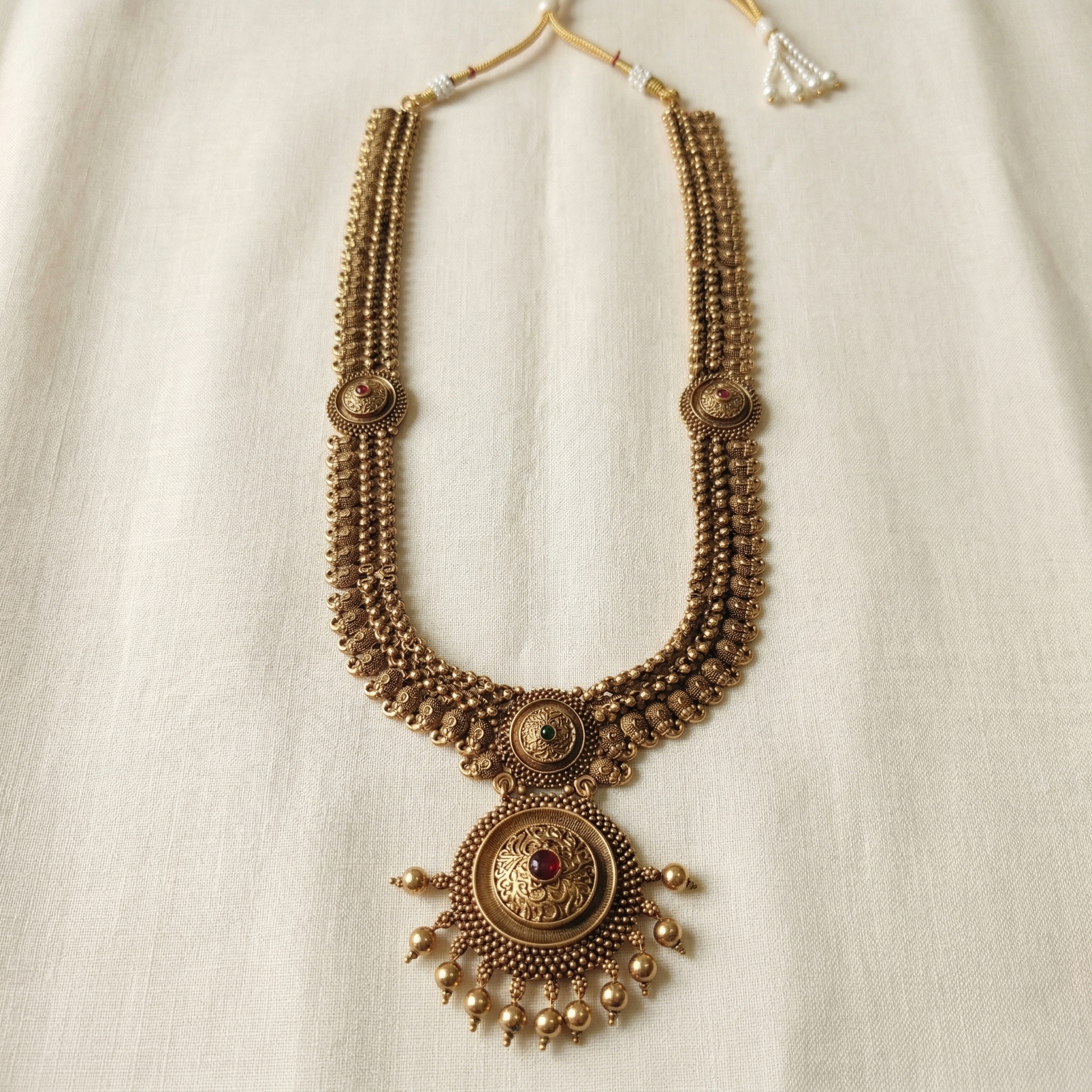 Decorative gold necklace with intricate designs on a light background