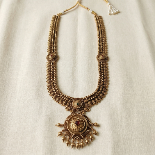 Decorative gold necklace with intricate designs on a light background