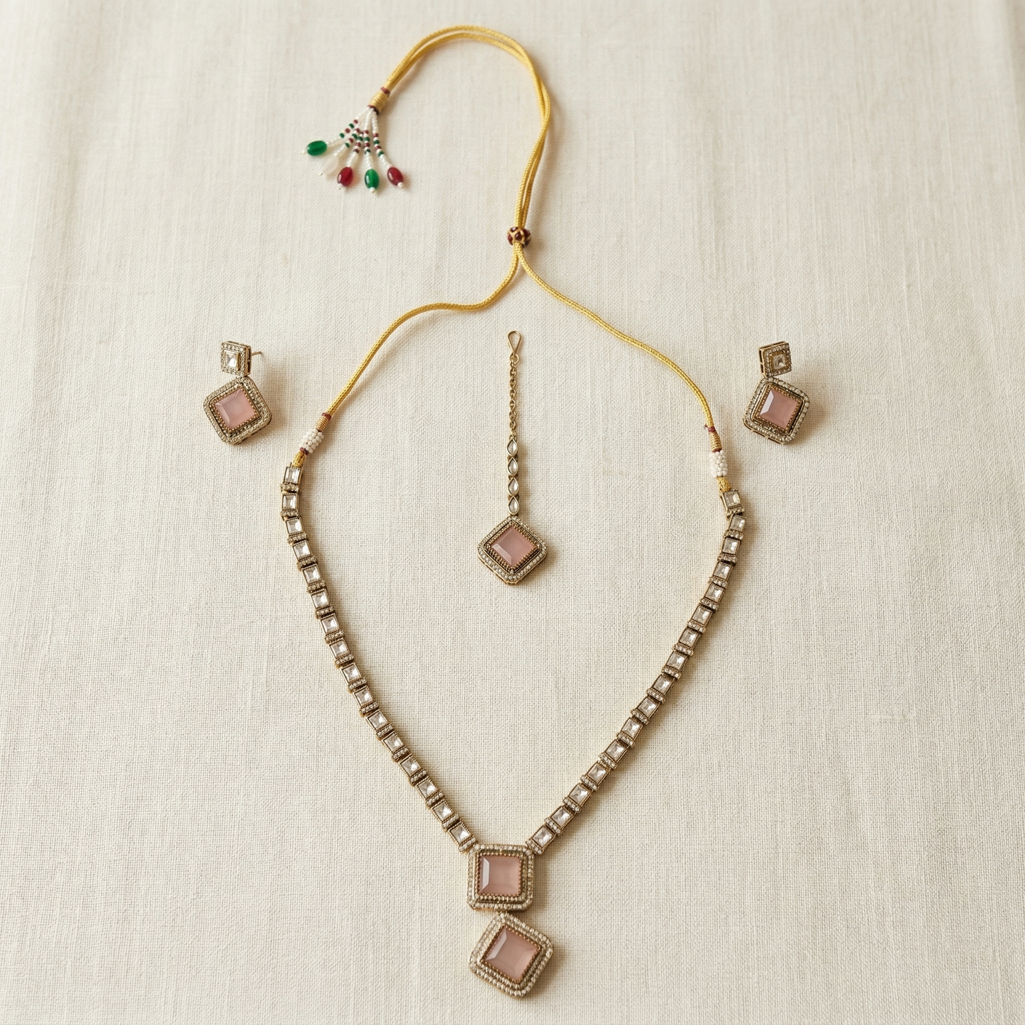 Necklace with square pendants and matching earrings on a textured beige background