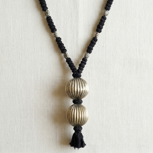 Necklace with black beads and gold spherical pendants on a light background