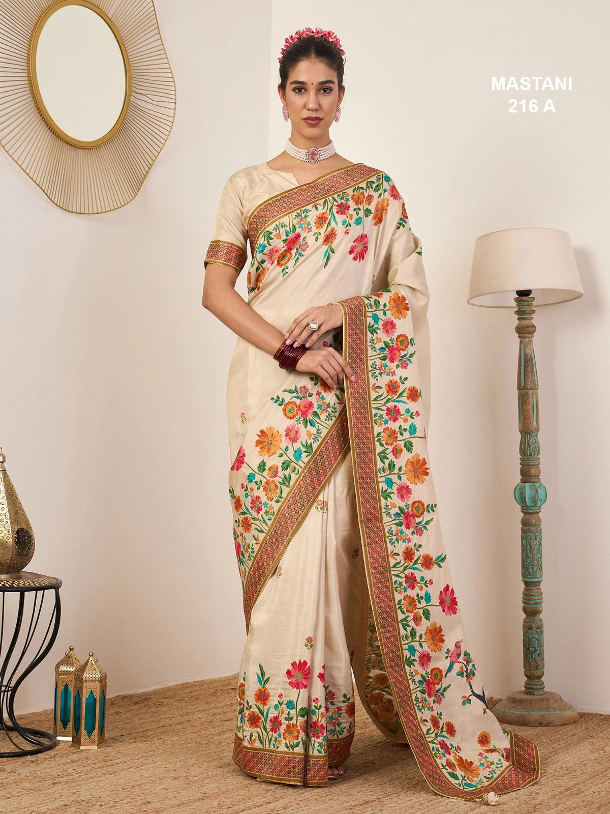 Woman wearing a cream saree with floral patterns in a room setting