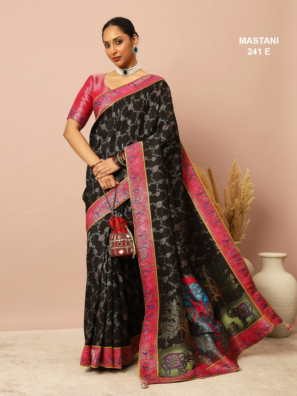 Woman wearing a black and red saree with a vase and plant in the background