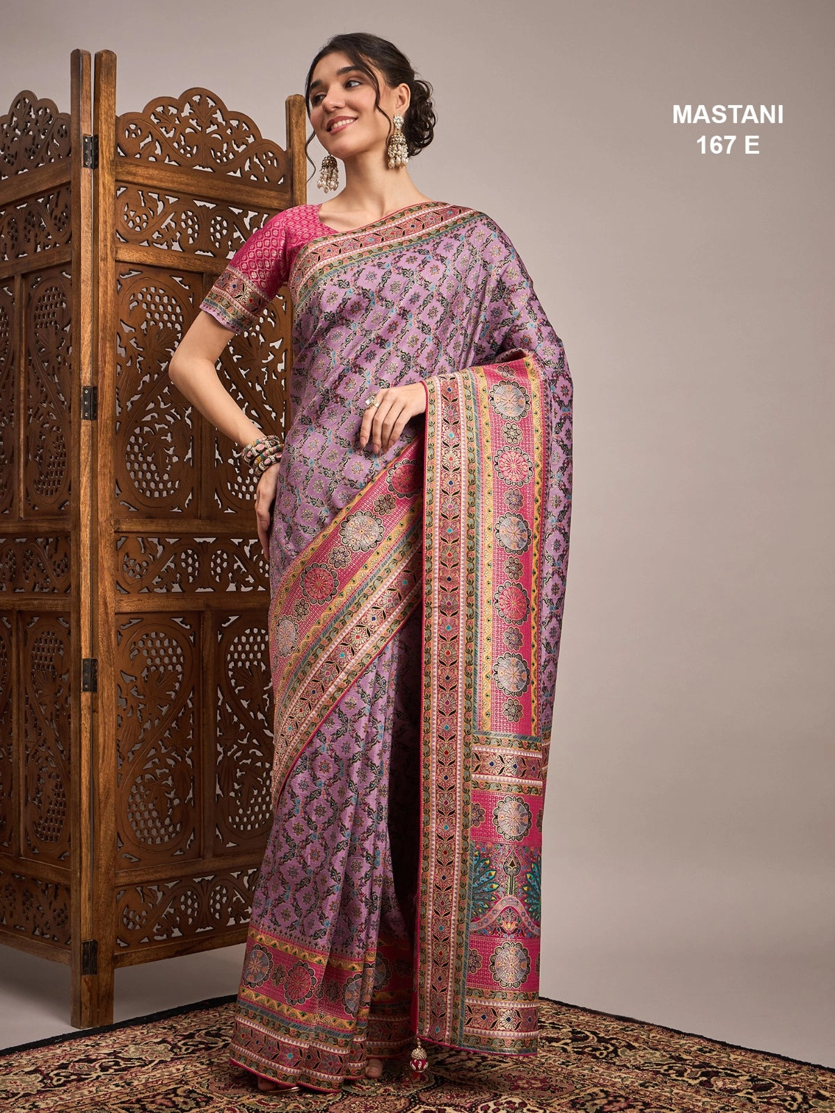 Woman wearing a patterned saree with a wooden screen in the background