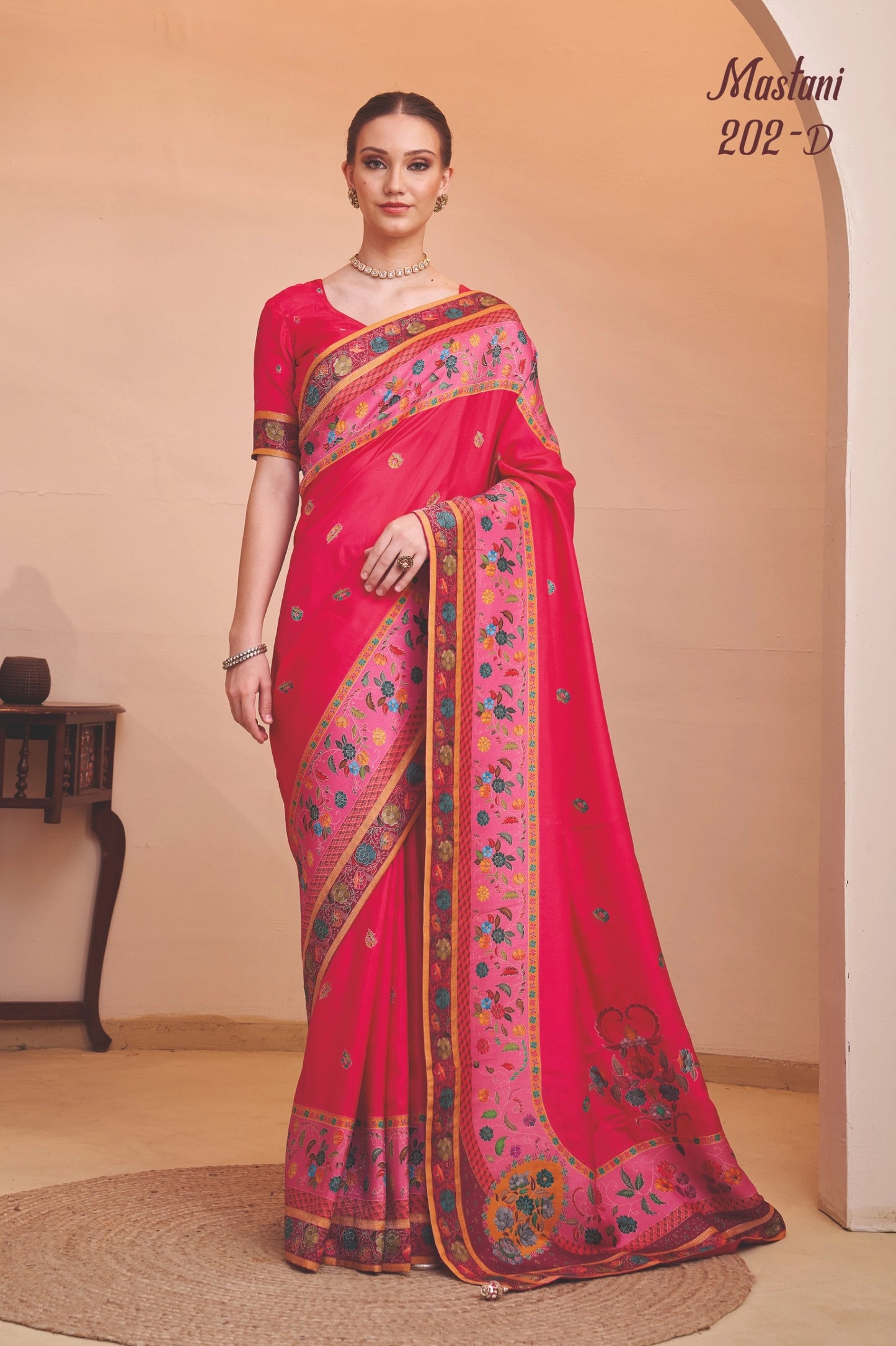Woman wearing a red saree with floral patterns in a room setting