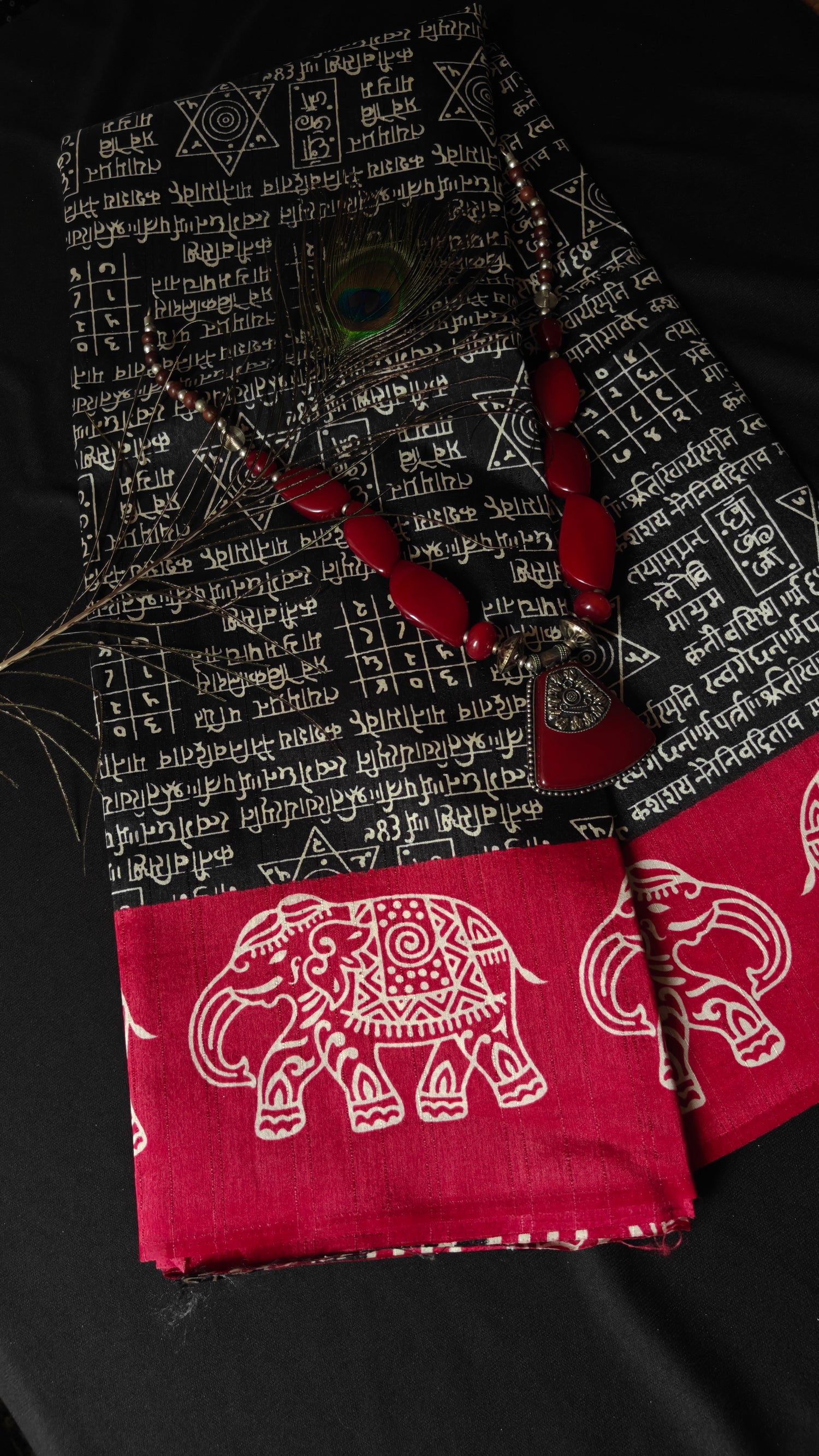 Red fabric with elephant design and black fabric with white patterns on a dark background