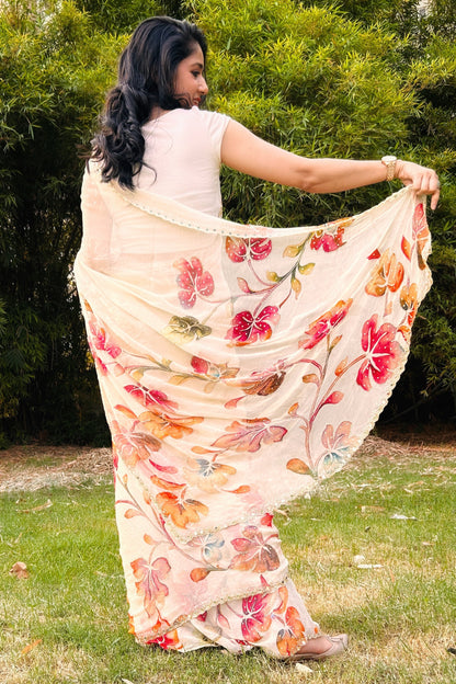 Woman wearing a floral saree outdoors with greenery in the background