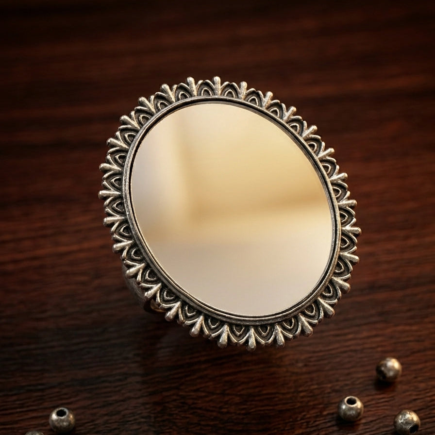 Decorative round mirror with intricate frame on a wooden surface