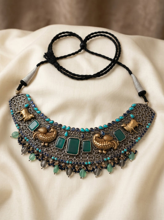 Decorative necklace with turquoise stones and intricate design on a beige fabric background