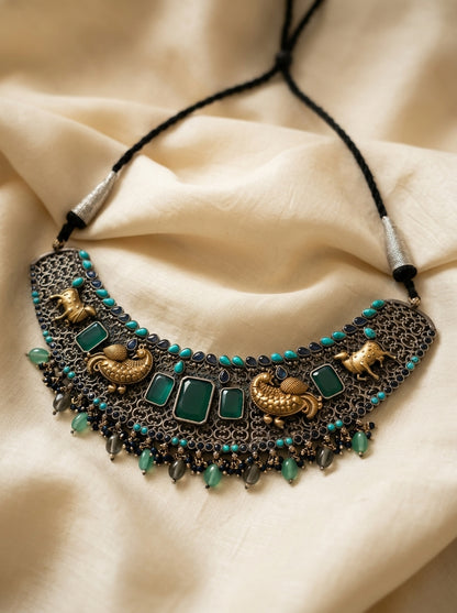 Ornate necklace with green stones on a beige fabric background