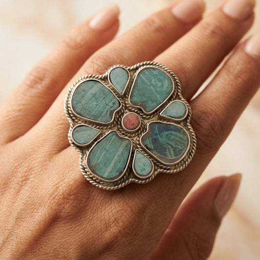 Turquoise floral ring on a hand with a blurred background
