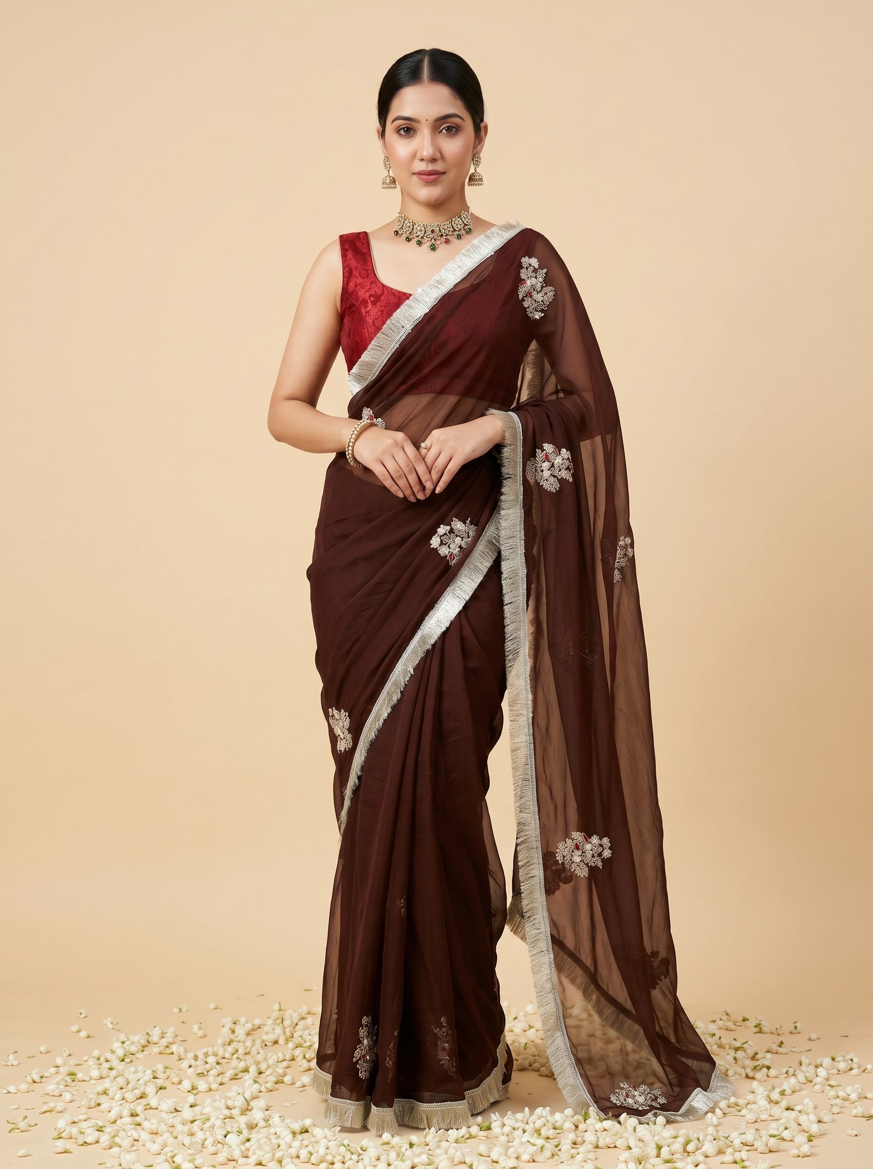 Woman wearing a brown saree with white border on a beige background