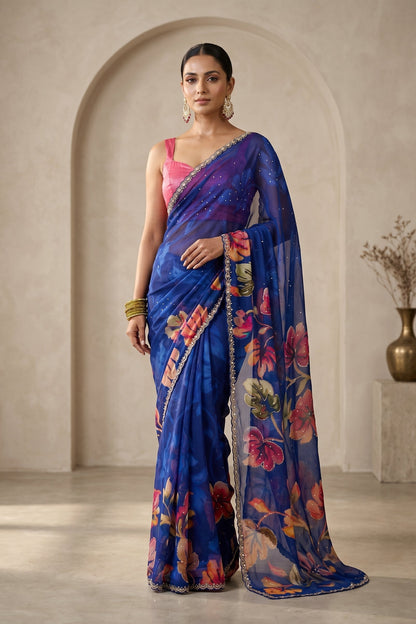 Woman wearing a blue saree with floral patterns in an indoor setting