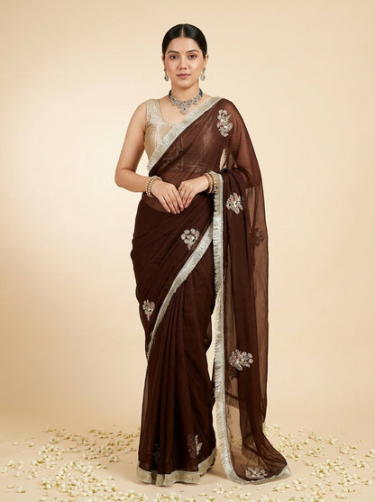 Woman wearing a brown saree with white embroidery on a beige background